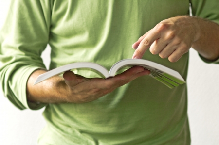 Close up of a man holding a book, pointing a verse with his index fingerの写真素材