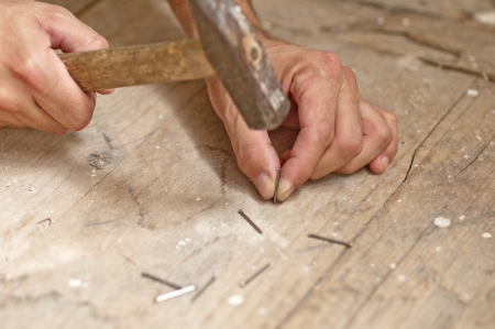 Man hands driving nail with hammer, building worksの写真素材