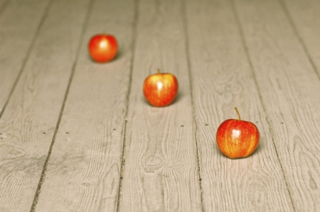 Three red apples in a row, over a wooden backgroundの写真素材