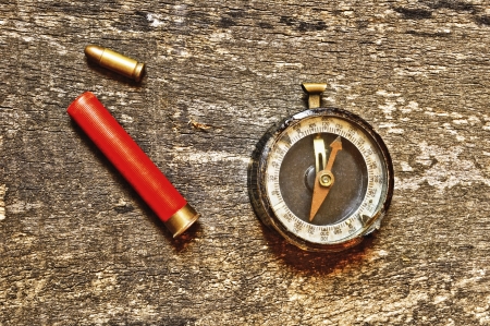 Compass and two bullets on old wooden background の写真素材