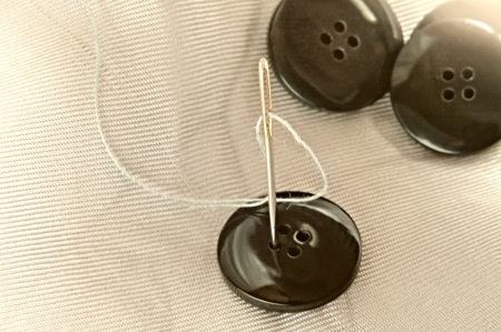 Buttons and threads with a needle closeup
