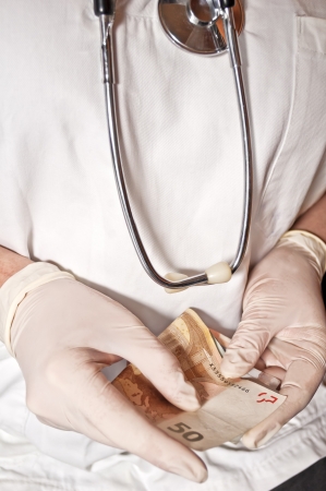 Bribe in medicine, doctor with money in handsの写真素材