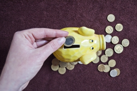 Hand putting coin into the ceramic piggy bank の写真素材