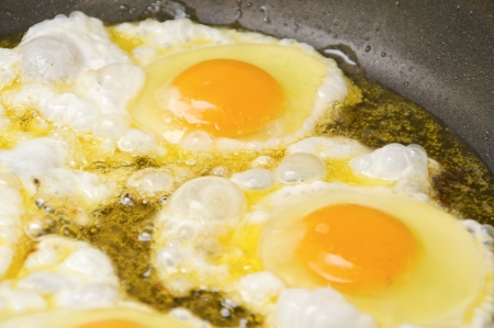 Close up view of the fried eggs on a frying pan の写真素材