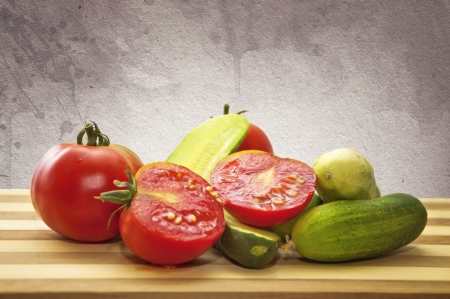 Tomatoes and cucumbers on a wooden plate の写真素材