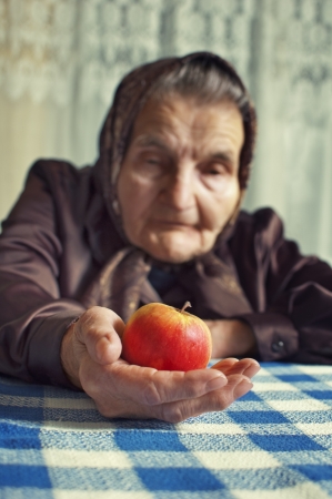 Old woman holding an apple  Selective focus on apple の写真素材