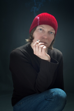 Beautiful woman with red cap smoking cigaretteの写真素材