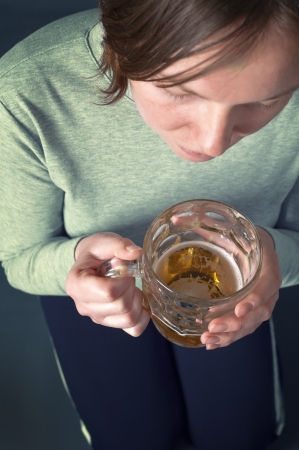 Young girl sitting on floor with light beer from the glass jug  One glass of beer a day concept  の写真素材