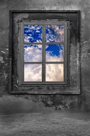 Old window in a cold concrete room, view on cloudy sky の写真素材