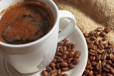 Closeup cup of coffee and coffee beans on jute background の写真素材