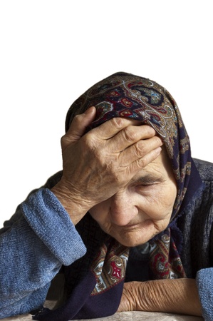 Portrait of a sad elderly woman holding her head in pain  の写真素材