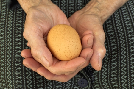One egg in elderly hands の写真素材