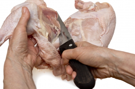 Hand with knife cutting chicken meat の写真素材