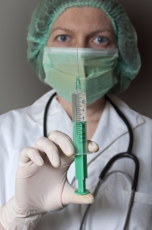 Doctor in mask holding a medical syringeの写真素材