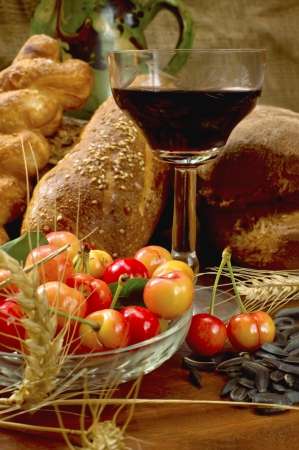 Still life with bread, cherrys, and wine on wooden table の写真素材
