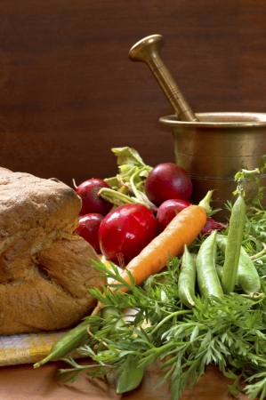 Tasty fresh vegetable and crunchy home made bread with old bronze mortar.の写真素材