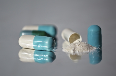 Capsule pills onto reflective grey surface  