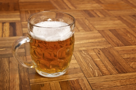 Mug fresh beer with cap of foam on wooden の写真素材