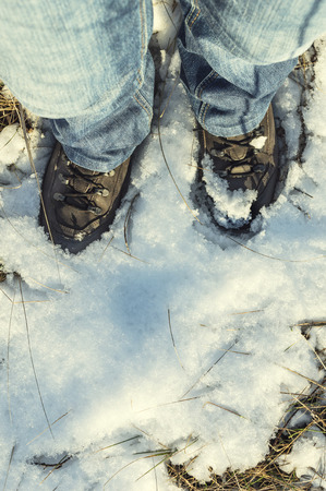 Brown boots covered in snow walking on a snowy field.の写真素材