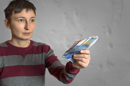 Woman holding swiss francs in hand, selective focus on swiss francs.の写真素材