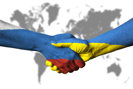 Russian flag and Ukraine flag across handshake in front of world map.の写真素材