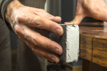 Handyman working with sandpaper on a wooden tableの写真素材