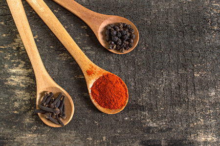 Spices in wooden spoon on rustic wooden table