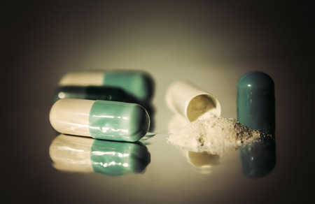 Close up of pills on gray background with reflection. Selective focus.