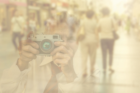 Elderly woman with camera. Double exposure image with unrecognizable people walking on street.の写真素材