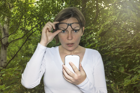 Surprised woman looking at phone seeing bad news or photos there with disgusting emotion on her...