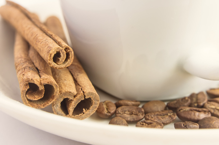 Close-up of fragrant cinnamon sticks, coffee beans and white cup. Selective focus.の写真素材