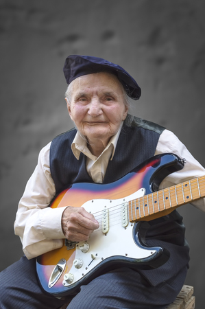 Elderly woman playing guitar. Selective focus.の写真素材