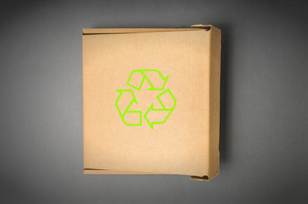 Cardboard box with recycle sign isolated on a gray background. Ecology concept.の写真素材