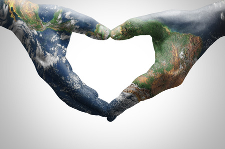 The hands of a young woman forming a heart patterned with a world map (furnished by NASA)の写真素材
