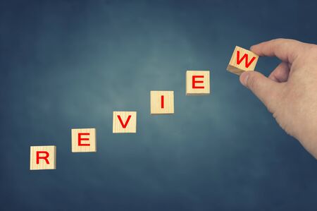 Hand putting wooden cube with alphabet REVIEW. Business conceptの写真素材