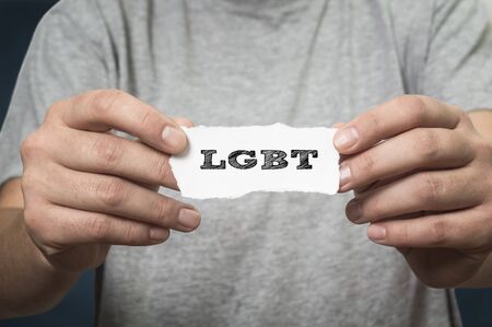 Caucasian woman holding a paper note in front of her with the text LGBTI written in it