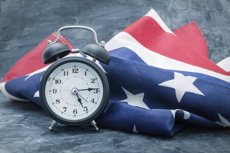 National flag of America and black alarm clock on dark backgroundの写真素材