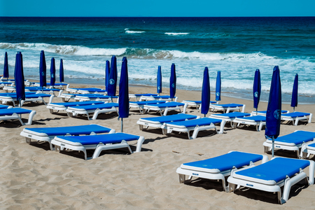 Empty beach umbrellas and chairs on an empty sandy coast early in spring at Limassol Cyprusの写真素材