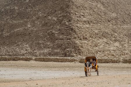 Giza, Egypt - 2018: Front view of tourists in a horse-drawn carriage with the ancient pyramids of Giza on backgroundのeditorial素材
