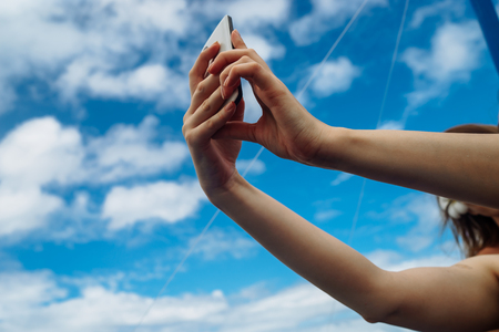 Phone in hand on blue sky with cloudsの写真素材