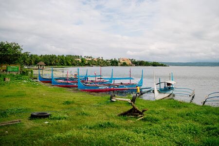 Phishing boat on a shore of beautiful Lake Taal, Philippines. Landscape of Luzon Island with volcano on the lake that changed the area geometry a few centuries ago. Dec 2018, Philippinesのeditorial素材