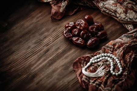 Table top view aerial image of decoration Ramadan Kareem holiday background.Flat lay accessory date with white rosary on modern rustic brown wood desk.space for creative design add text.の写真素材