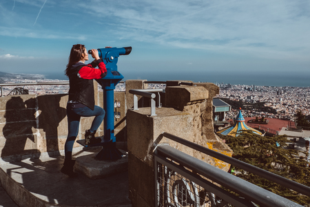 Woman looking at the city of Barcelona from Tibidabo, using a coin operated pair of binoculars. 2019の写真素材
