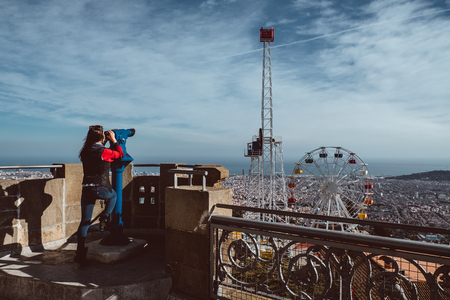 Woman looking at the city of Barcelona from Tibidabo, using a coin operated pair of binoculars. 2019の写真素材