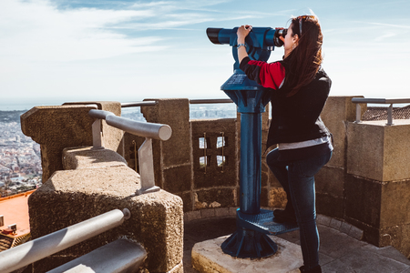 Woman looking at the city of Barcelona from Tibidabo, using a coin operated pair of binoculars. 2019の写真素材