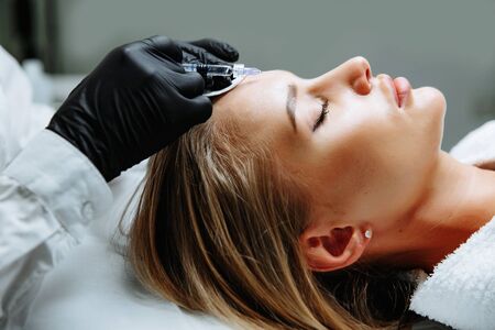 Portrait of female patient having modern noninvasive procedure of rhinoplasty, Doctor injects substance in patient nose, Aesthetic corrective treatments conceptの写真素材