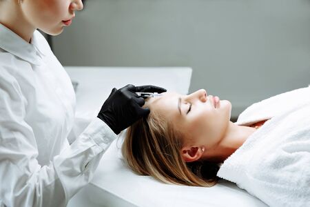 Beautiful woman getting lifting injection in forehead. Close-up woman face injection. cosmetology clinicの写真素材