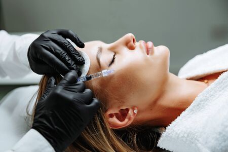 Young woman receiving plastic surgery injection on her face, closeupの写真素材