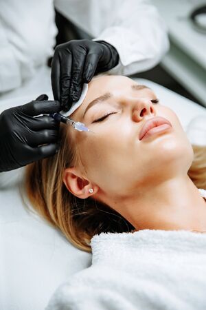 Young woman receiving plastic surgery injection on her face, closeupの写真素材