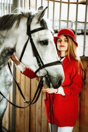 Young female rider with horse inside stable. equestrian sportの写真素材